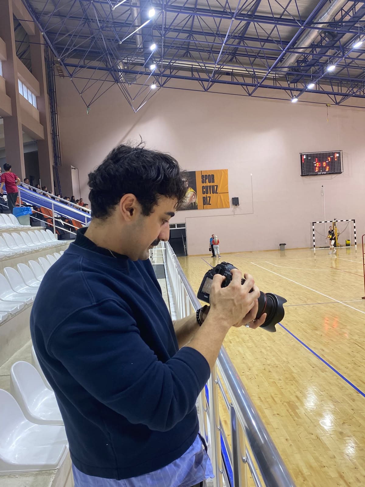 A photographer checking the camera while covering a match in a sports hall